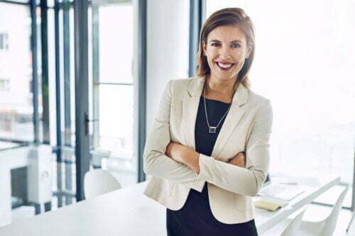 business woman crossing her arms in an office and smiling at the camera